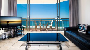 A balcony with a view of the sea, a TV, a coffee table, and a sofa. - Seacrest Beachfront Holiday Apartments (Surfers Paradise)