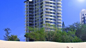 A high-rise hotel with multiple balconies, surrounded by trees and a sandy beach. - Seacrest Beachfront Holiday Apartments (Surfers Paradise)
