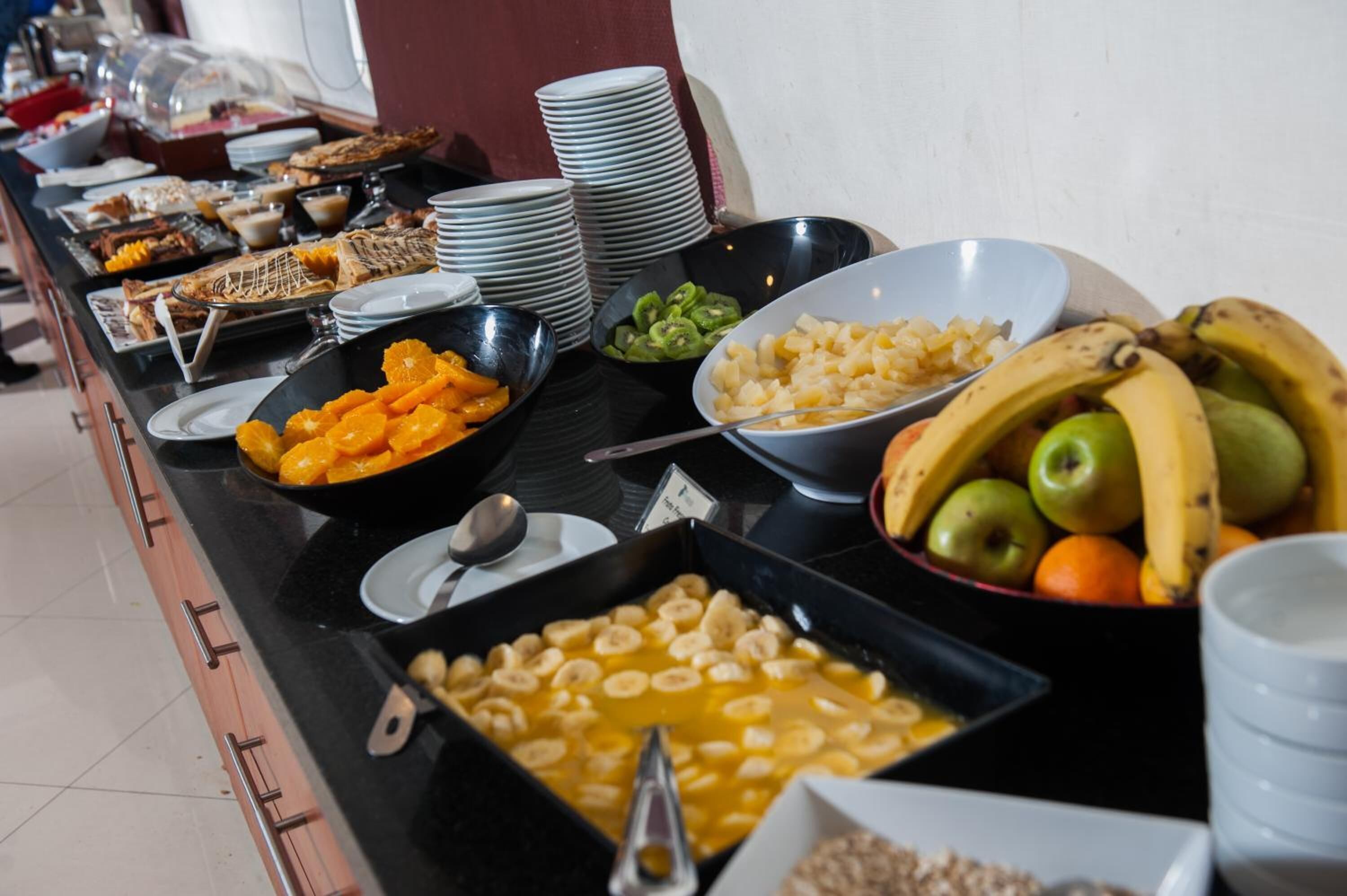 A buffet with various food items including fruits, pastries, and a bowl of bananas.