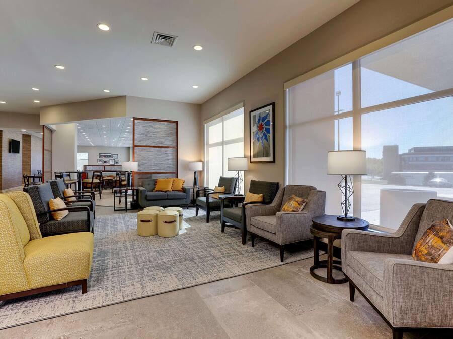 A spacious hotel lobby with multiple seating areas, a reception desk, and large windows offering views of the outside.