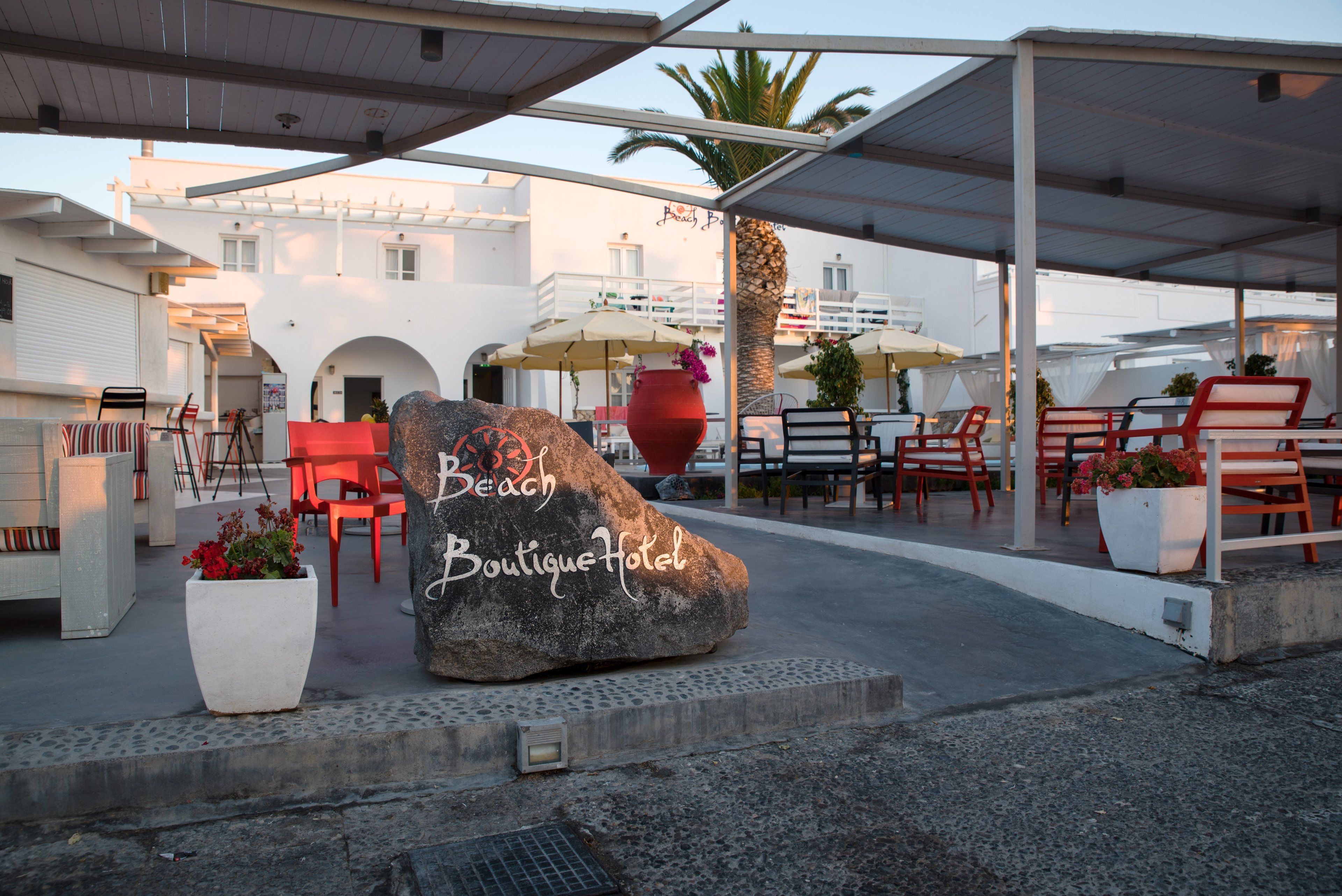 A beach boutique hotel with outdoor seating, a large rock with the hotel's name, and a covered patio area.