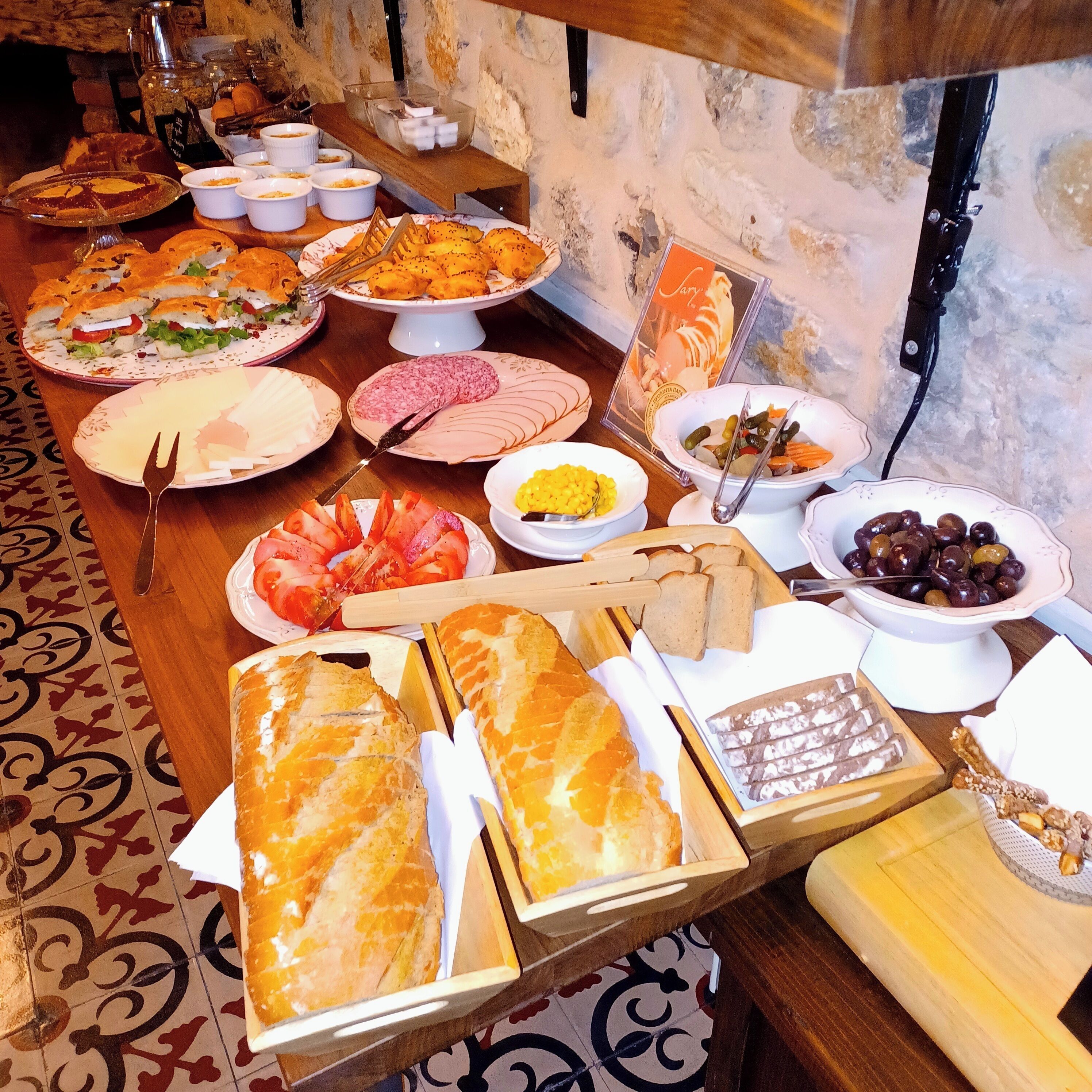 Une table de buffet proposant divers aliments, notamment du pain, de la viande et des légumes.