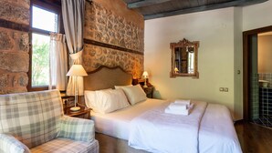 A room with a bed, a chair, a lamp, a mirror, and a stone wall. - To Palio Litohoro (Dio-Olympos)