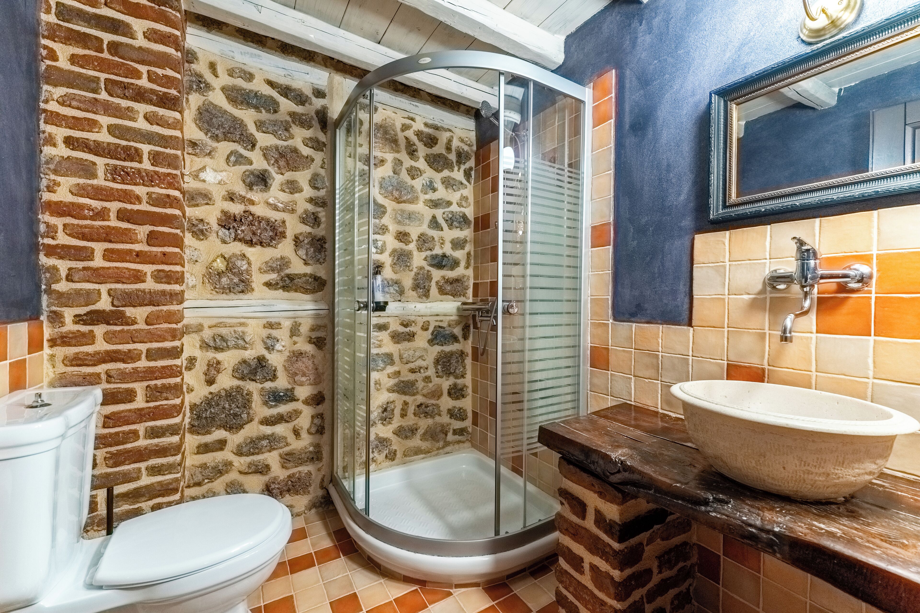 Une salle de bain avec une douche à parois de verre, des toilettes et un lavabo avec un miroir au-dessus.