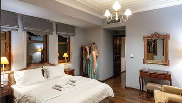 A hotel room with a large bed, bedside lamps, a vanity with a mirror, and a wooden desk.