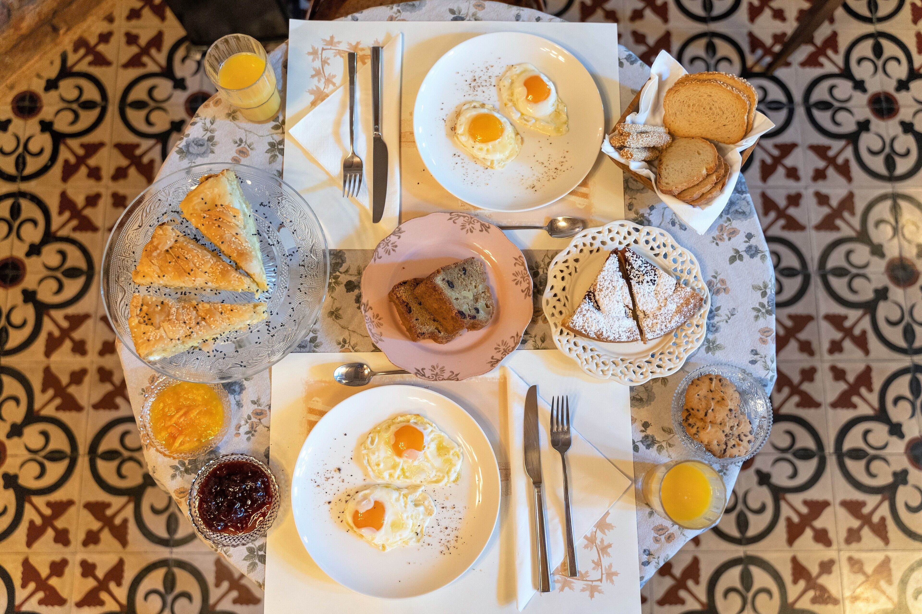 A breakfast table with various dishes including eggs, pastries, and fruit.