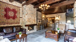 A spacious living area with a stone fireplace, leather sofas, and a chandelier. - To Palio Litohoro (Dio-Olympos)