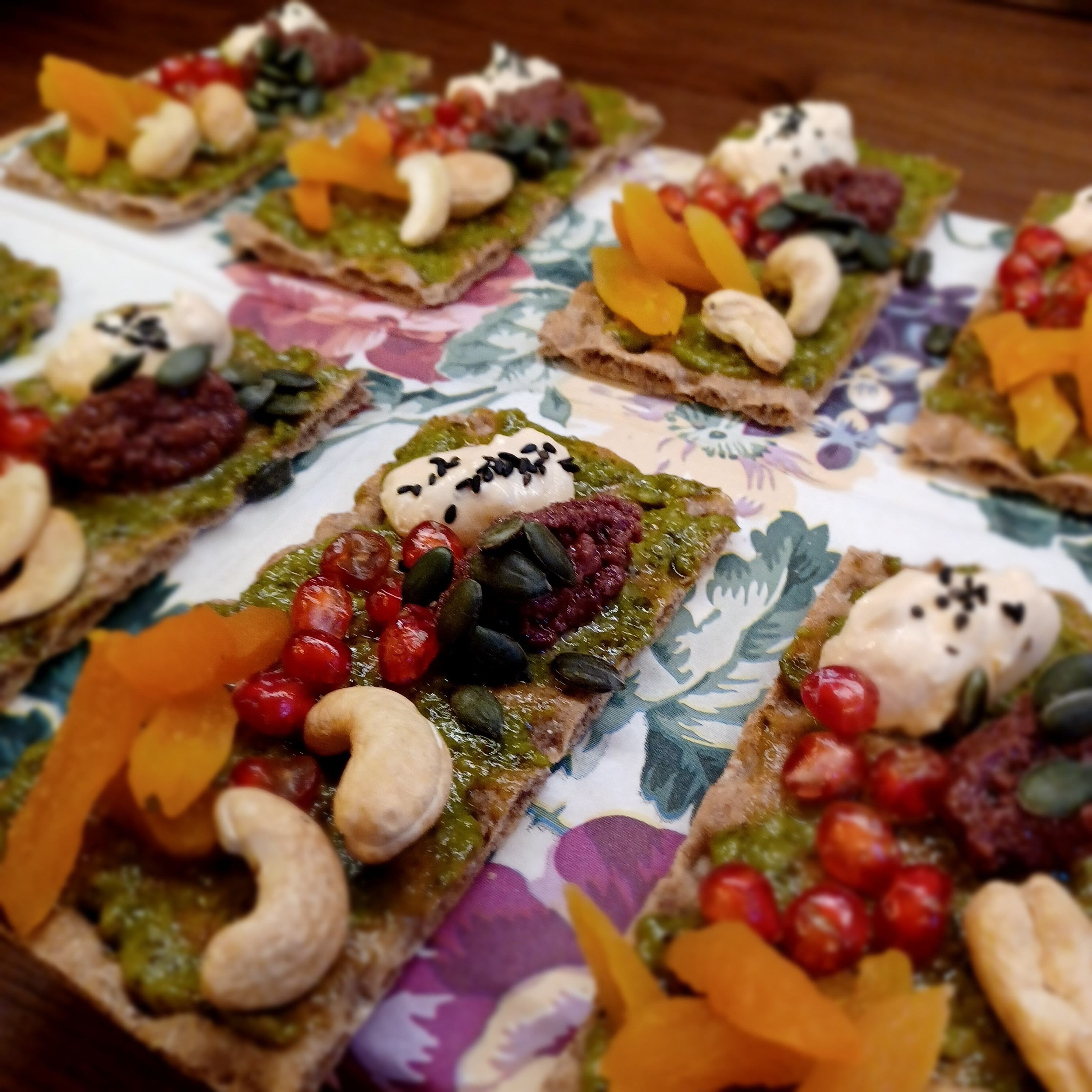 A table with various food items, including sandwiches and pastries, arranged on a patterned tablecloth.