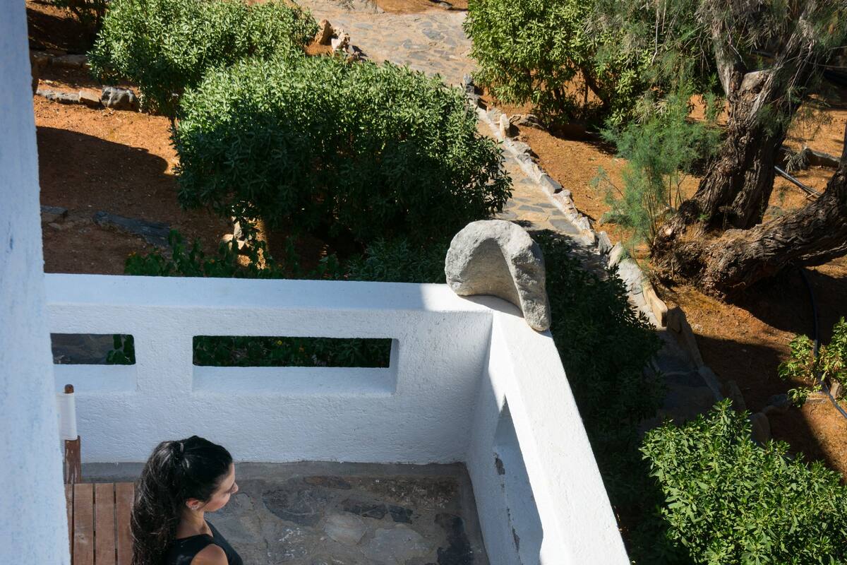 A stone-tiled patio with a wooden chair and a white wall.