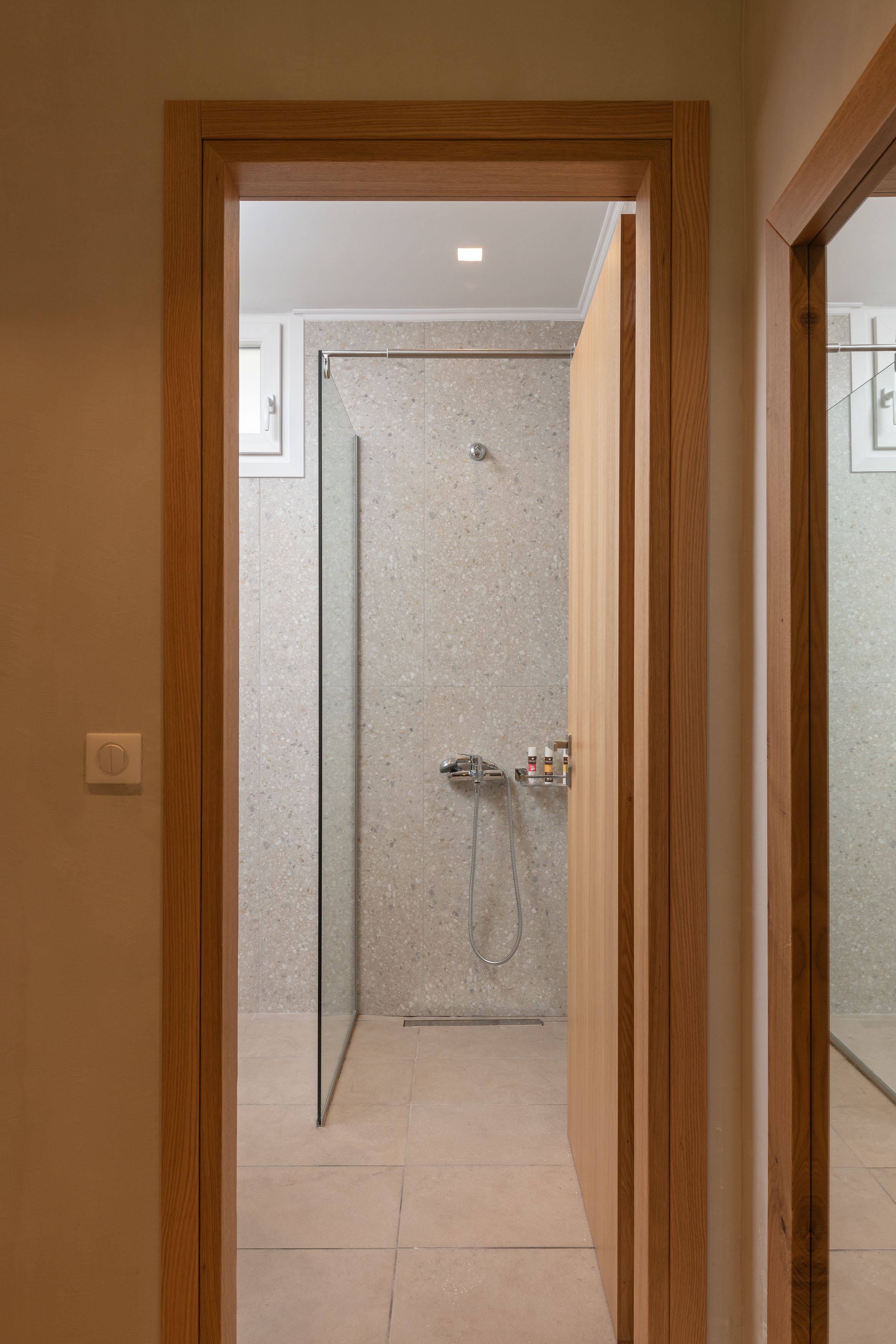 A modern bathroom with a glass shower enclosure, a visible showerhead, and a control panel.