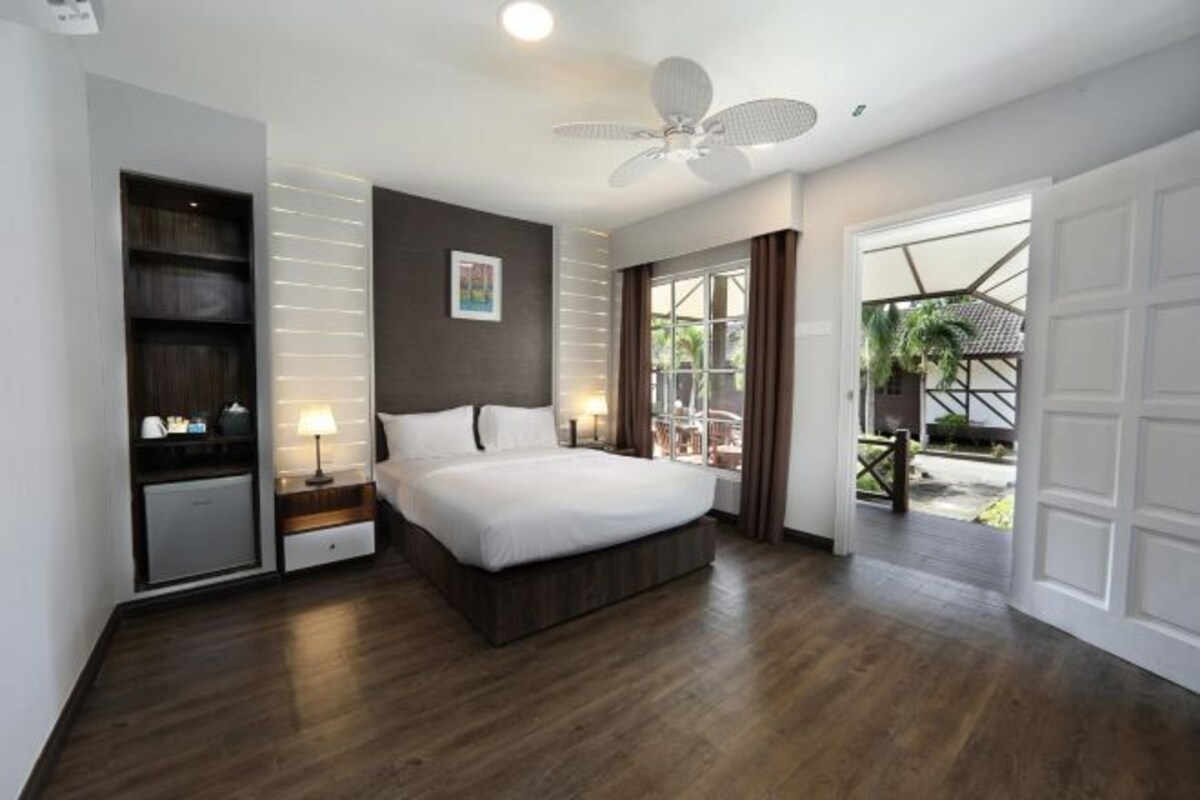 A modern bedroom with a large bed, a ceiling fan, a built-in wardrobe, and a view of the outdoors.