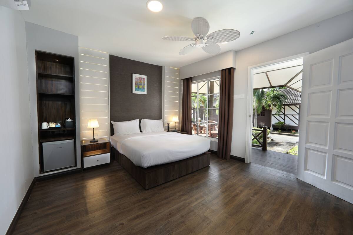 A modern bedroom with a large bed, built-in shelving, a ceiling fan, and a view of the outdoor patio.