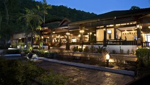 A hotel with a covered outdoor area, multiple rooms, and a view of a forested hill. - Perhentian Island Resort (Pulau Perhentian Besar)