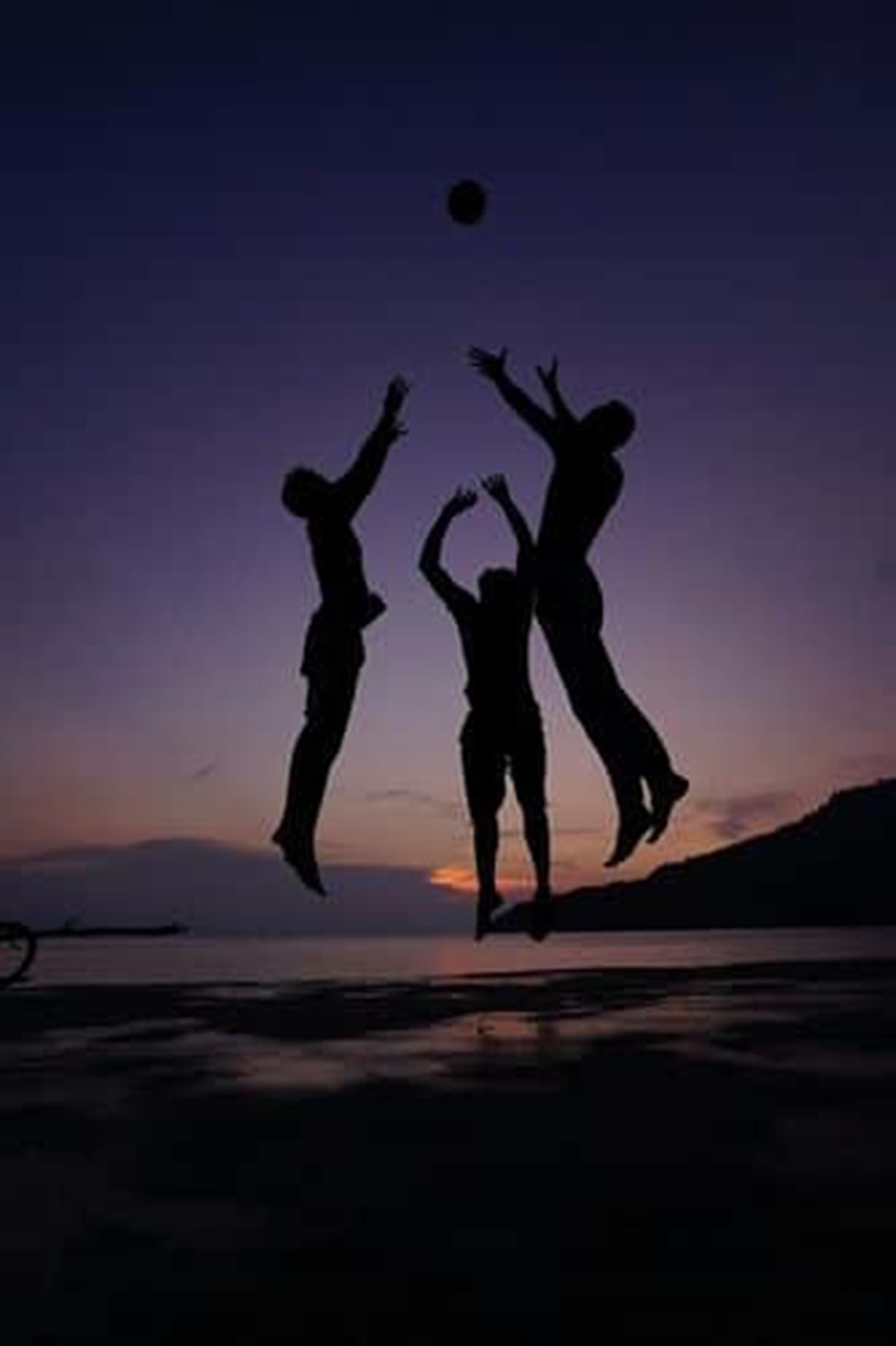 Siluetas de personas saltando contra un fondo de atardecer.