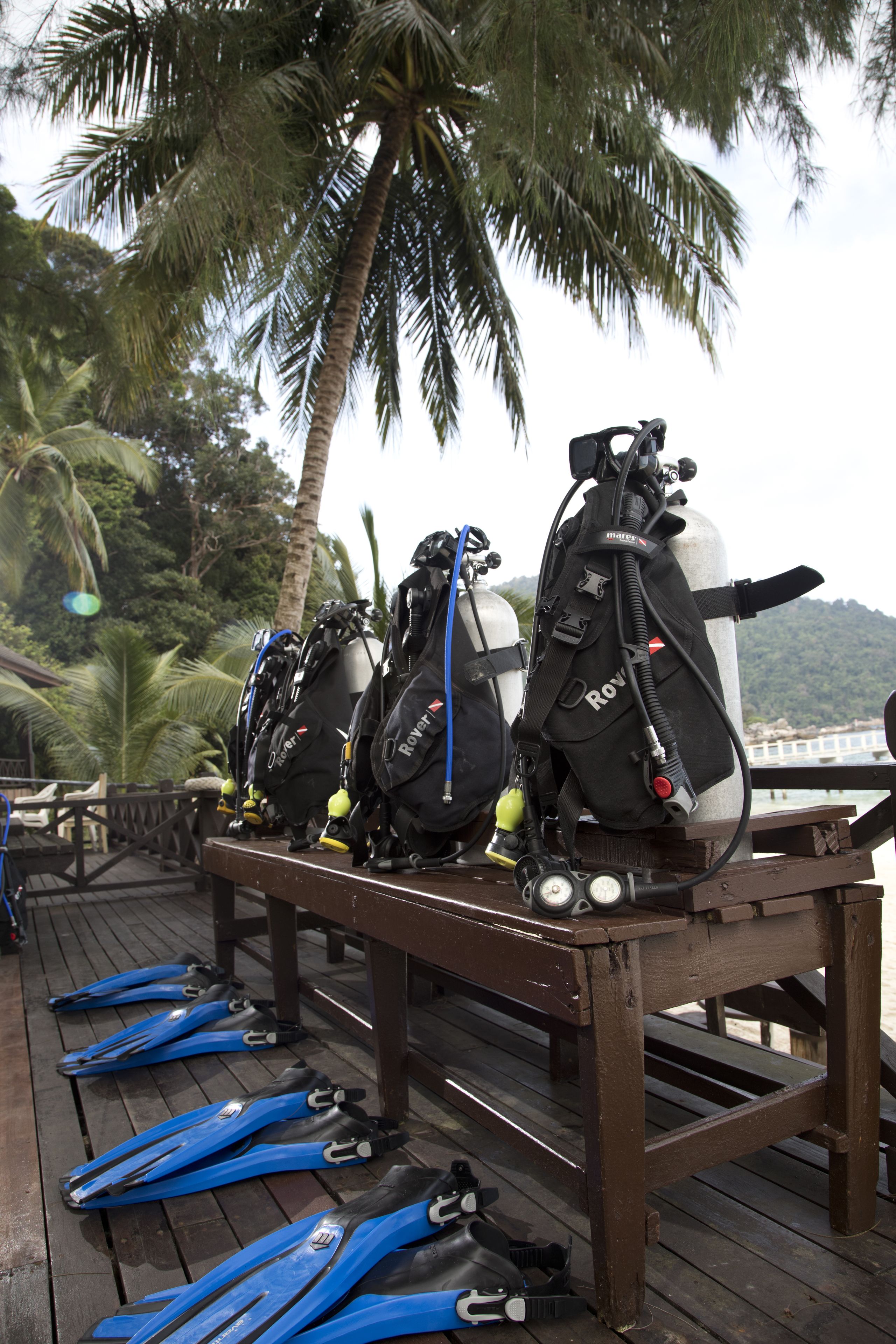 A wooden deck with scuba diving gear and fins.