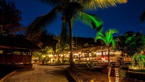 A nighttime view of a resort with palm trees, a pathway, and illuminated buildings. - Perhentian Island Resort (Pulau Perhentian Besar)