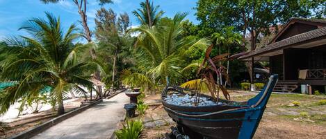 A pathway lined with palm trees and a traditional boat sculpture.
