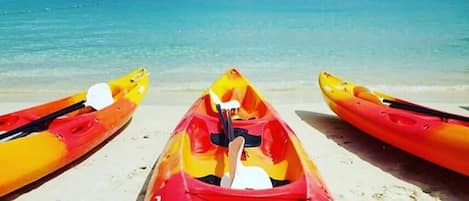 A beach with three kayaks lined up on the sand, facing the ocean.