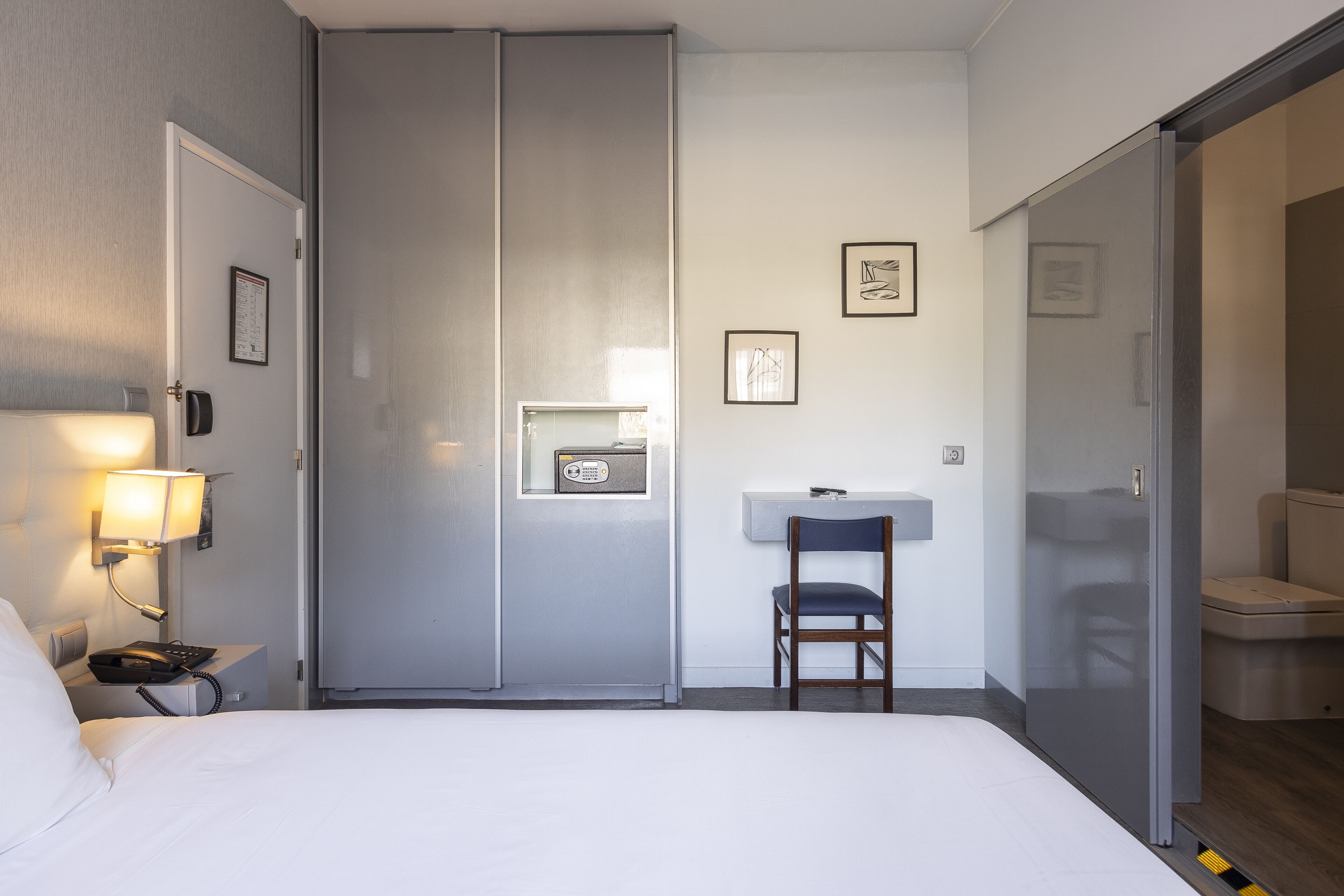 Ein Hotelzimmer mit Bett, Schreibtisch mit Stuhl, Telefon, Radio und Toilette.