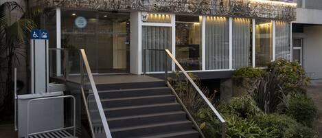 A hotel entrance with a ramp and stairs, a wheelchair-accessible sign, and a sign indicating a clean room.