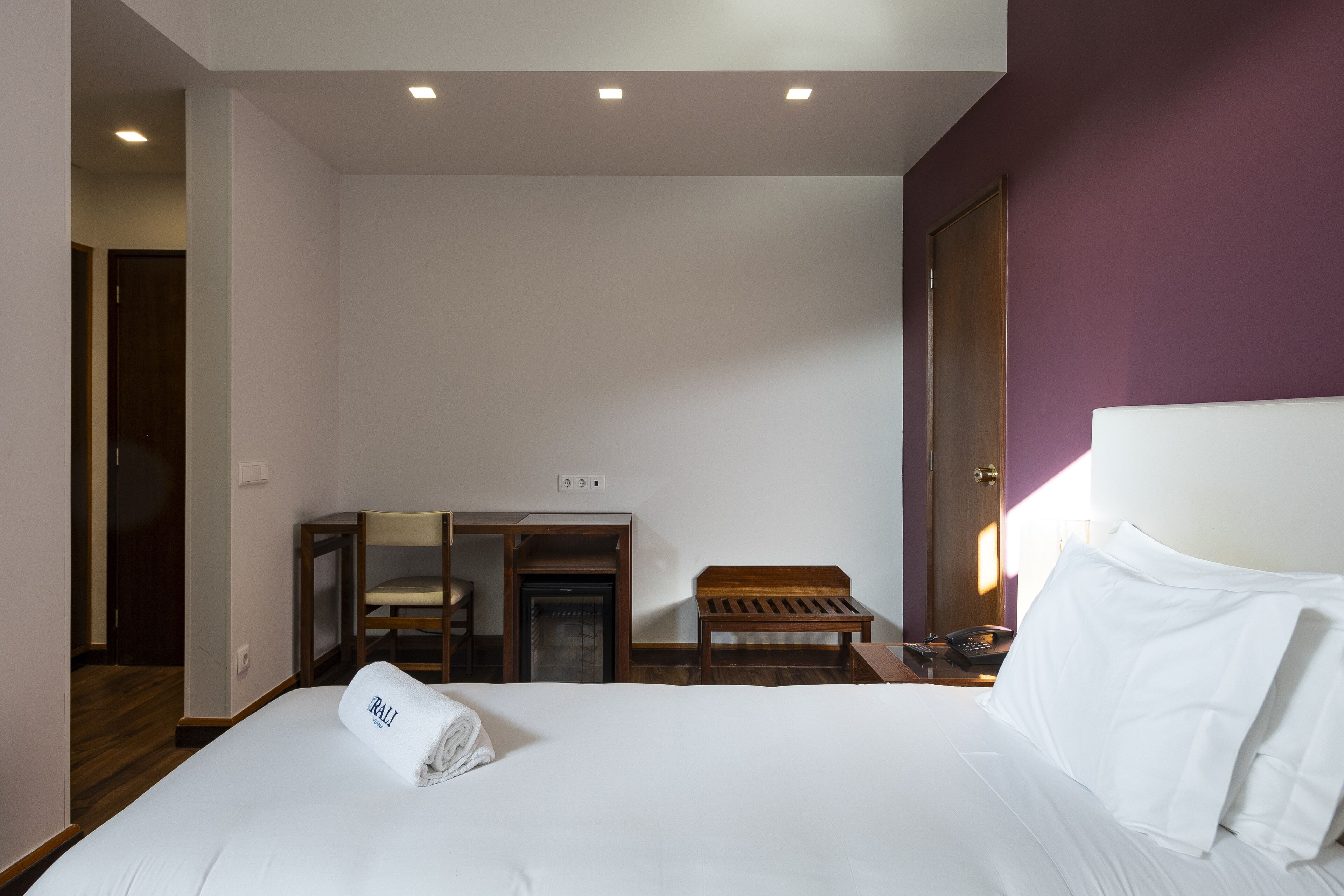 A hotel room with a bed, a desk, a chair, and a small table.