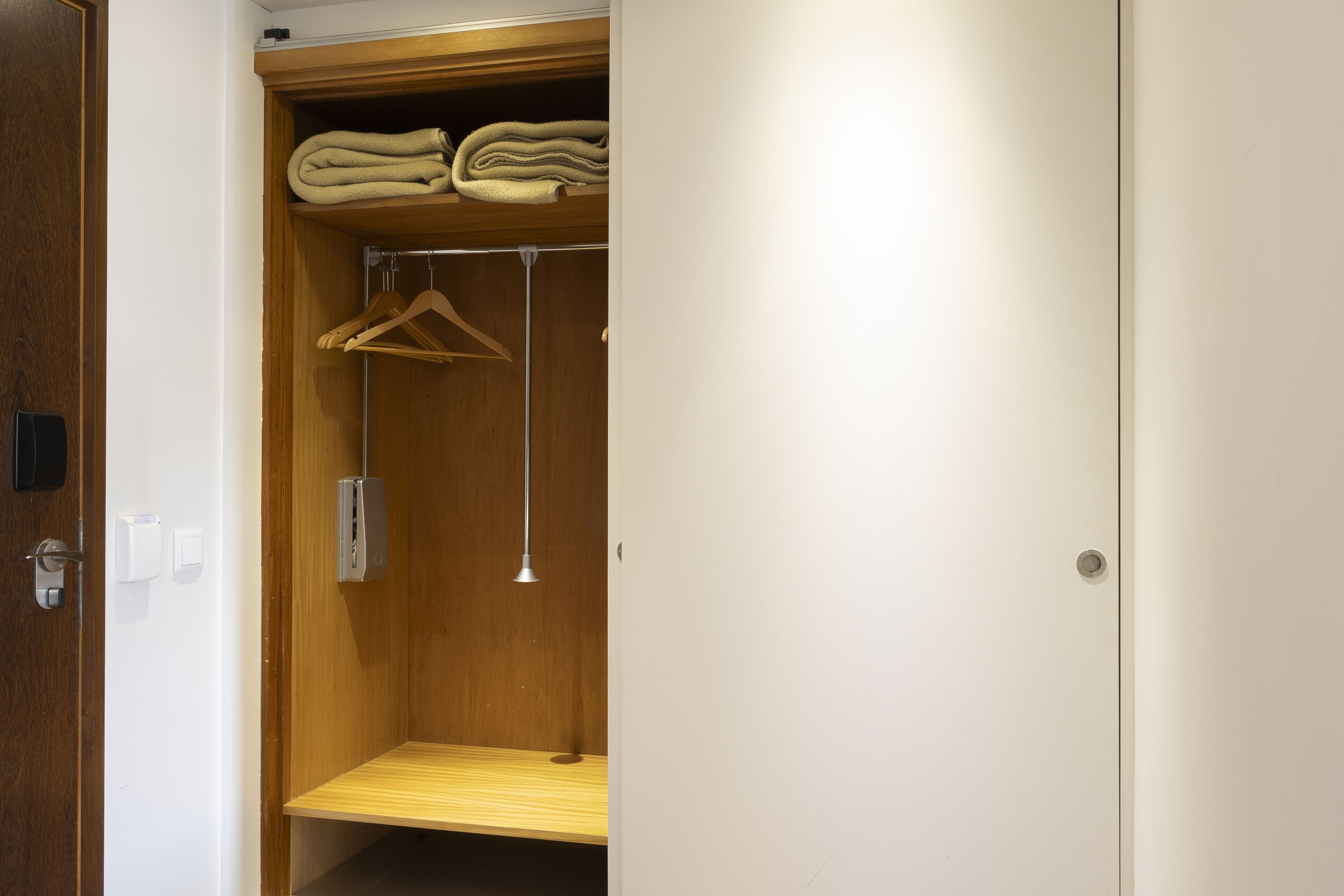 A walk-in closet with wooden shelves, a hanging rack, and a bench.
