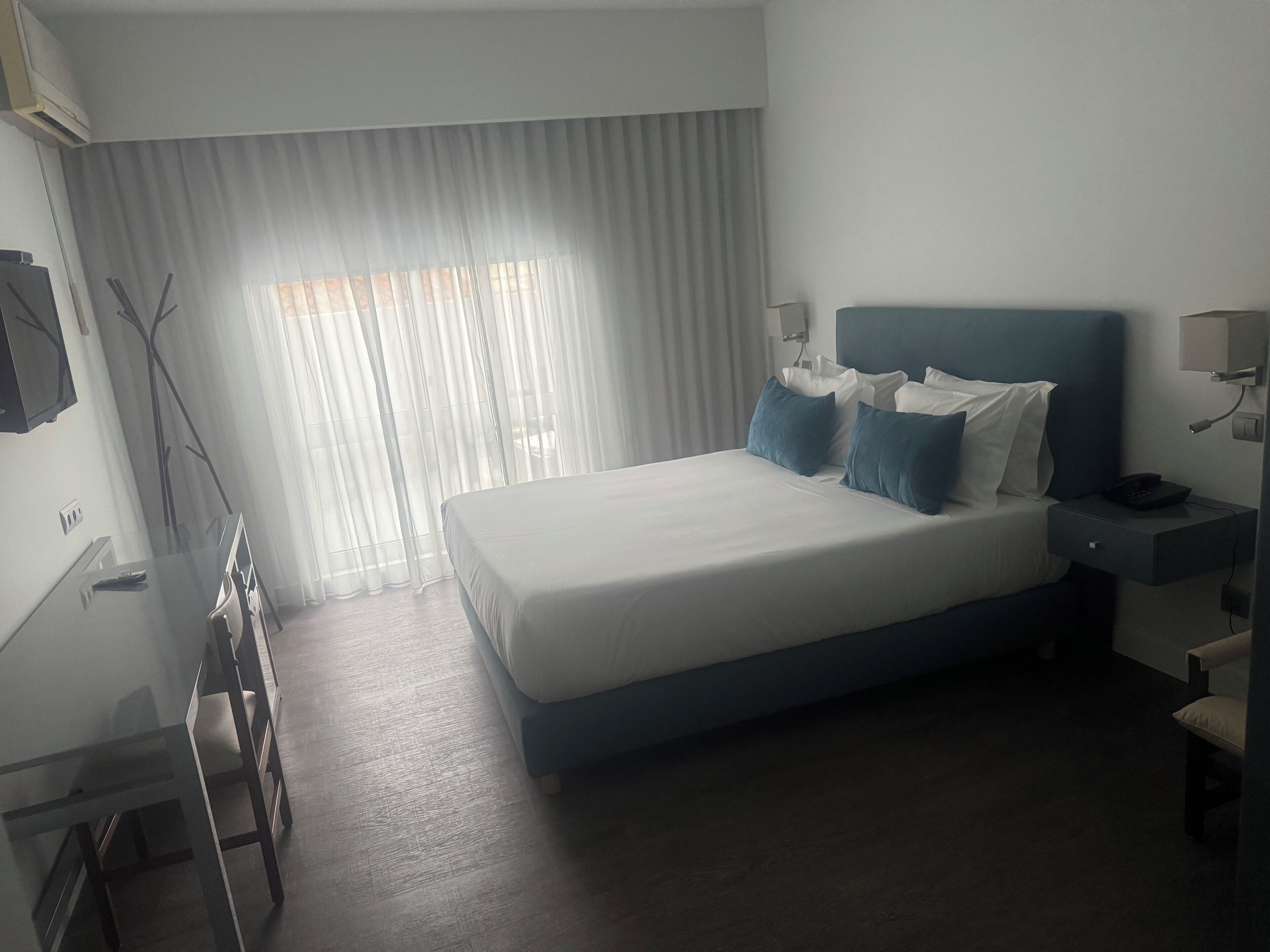 Una habitación de hotel moderna con una cama grande, mesitas de noche, un escritorio y una silla.