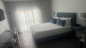 Una habitación de hotel moderna con una cama grande, mesitas de noche, un escritorio y una silla.