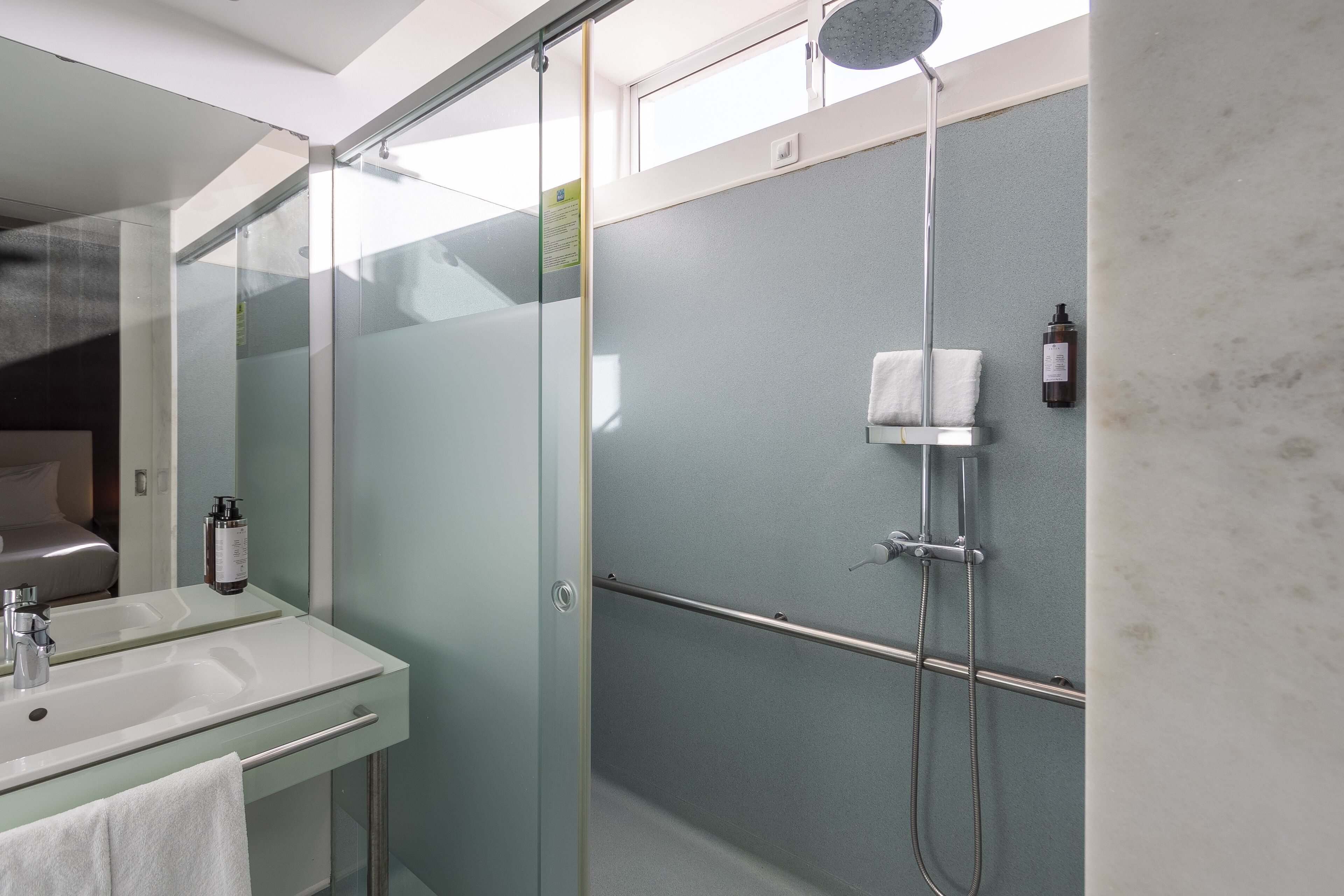 A modern bathroom with a glass shower enclosure, a sink with a towel, and a mirror.