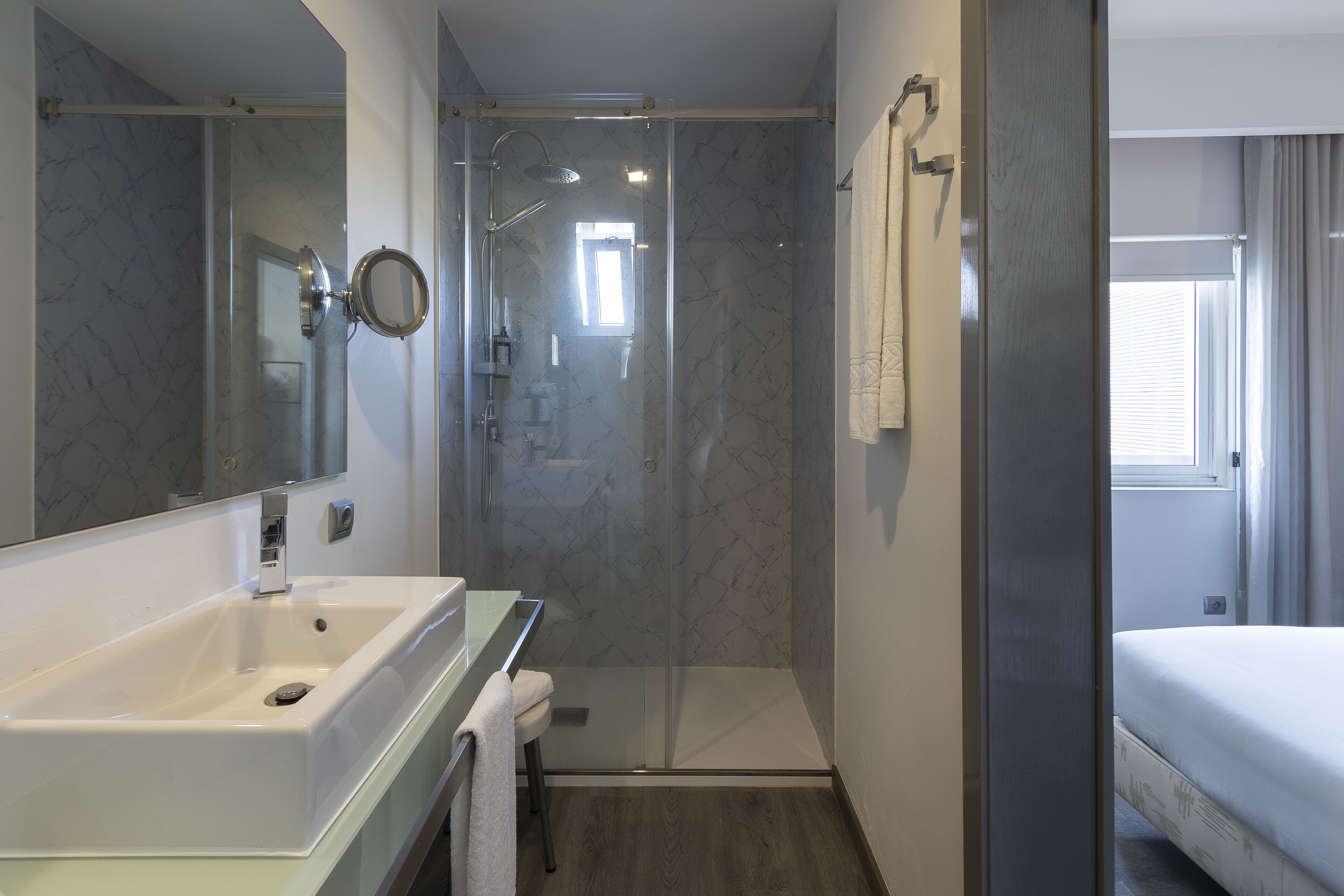 Une salle de bain moderne avec une douche à parois de verre, un lavabo blanc et un grand miroir.