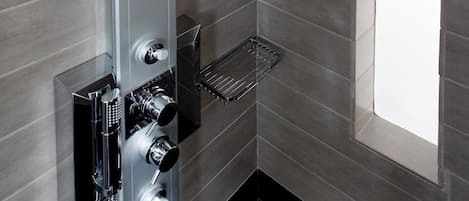 Eine moderne Dusche mit mehreren Bedienelementen und einer Glasablage.