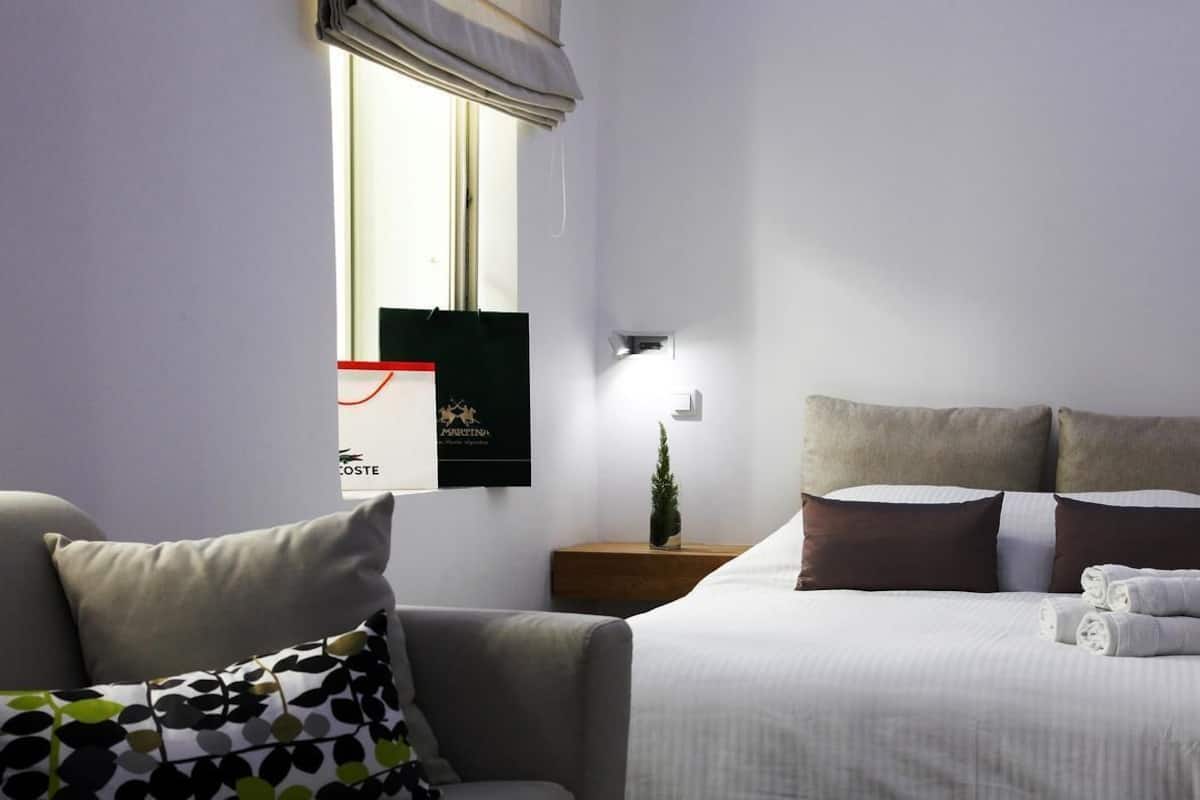 A hotel room with a bed, a nightstand, a small plant, and a window with a view.
