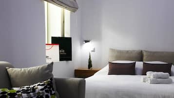 A hotel room with a bed, a nightstand, a small plant, and a window with a view.