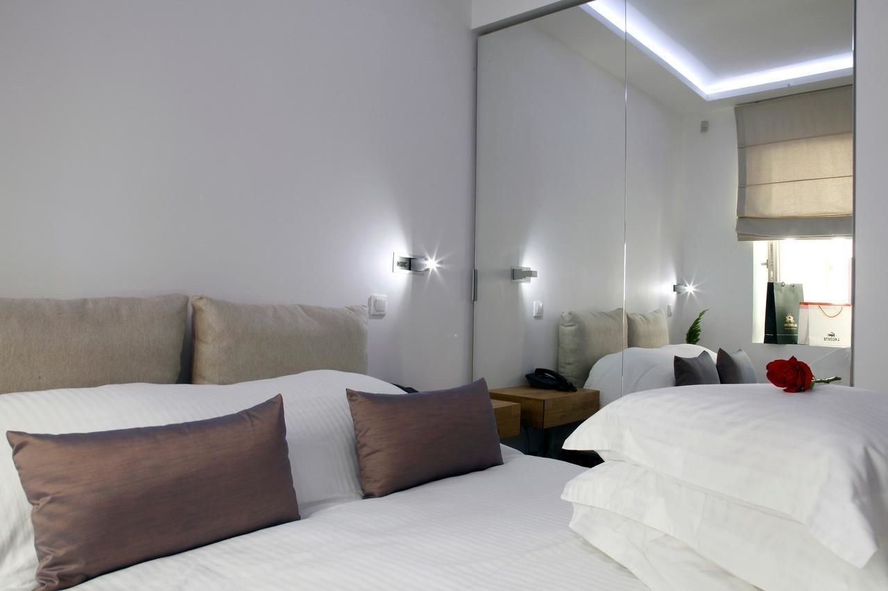 A modern hotel room with a large bed, bedside tables, a mirror, and a nightstand.