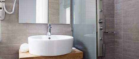 Een moderne badkamer met een ronde wastafel, een spiegel, een douchecabine met glazen wanden en een handdoekrek.