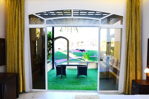 A room with a sliding glass door leading to a patio with a small table and chairs. - Samharam Resort Salalah (Salalah)