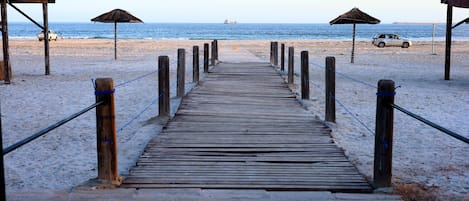 Een privéstrand, ligstoelen aan het strand, parasols, een strandbar