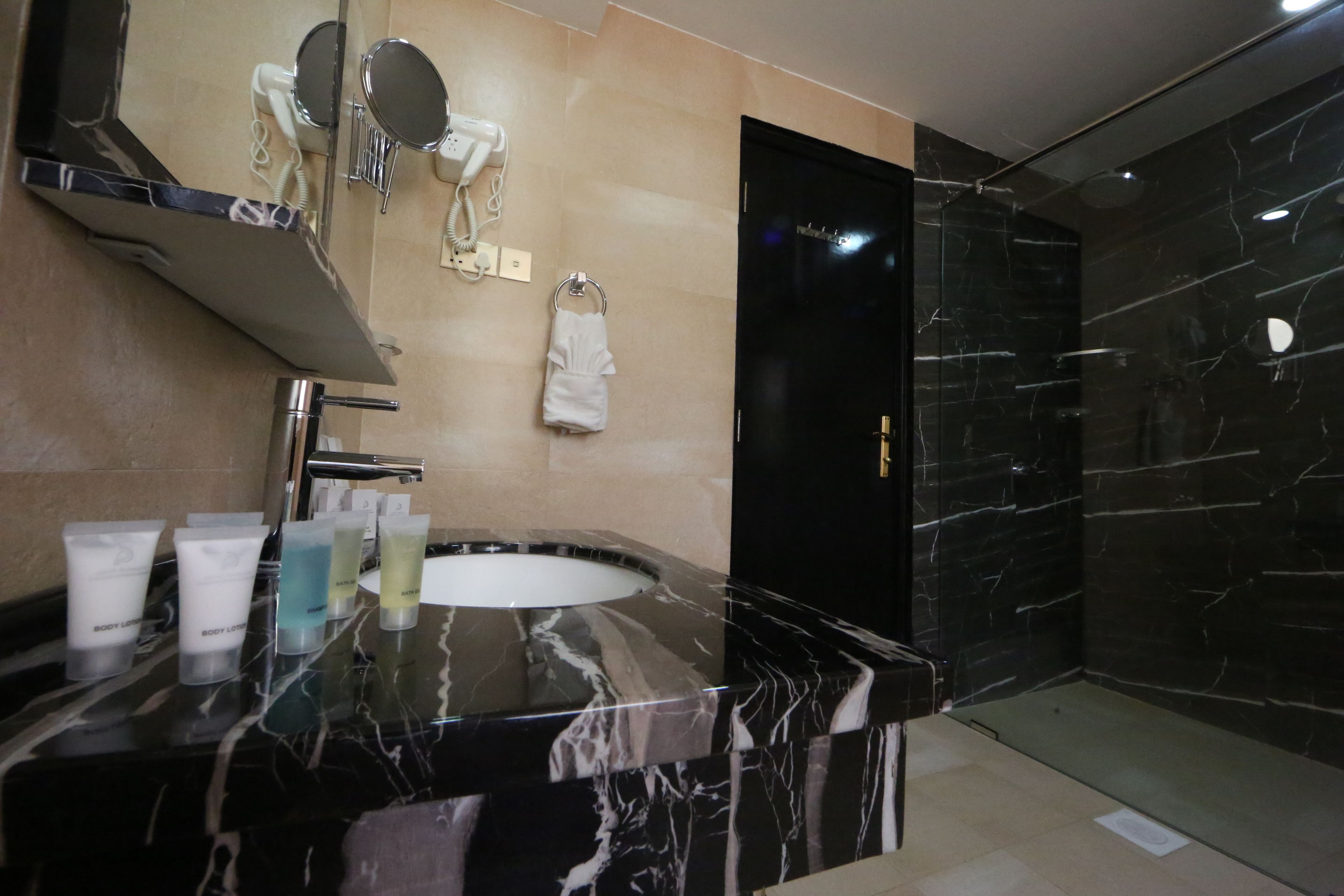Un bany modern amb un lavabo de marbre, un assecador, un mirall i un suport per a tovalloles.