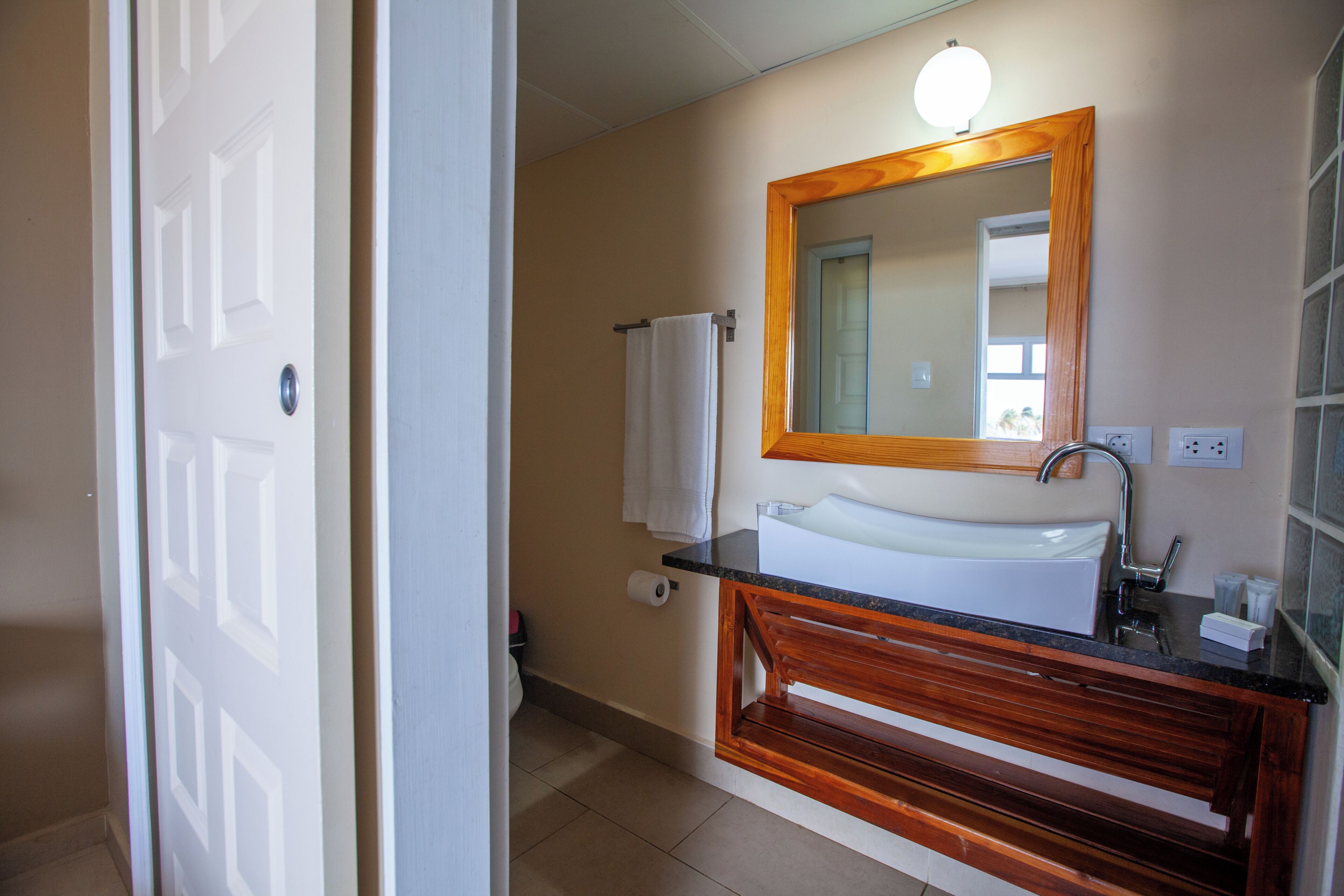 A bathroom with a wooden vanity, a sink, a mirror, and a towel rack.