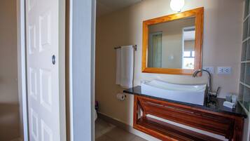 Un baño con tocador de madera, un lavabo, un espejo y un perchero para toallas.