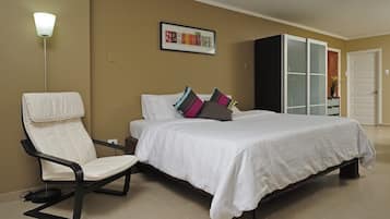 A bedroom with a bed, a chair, a wardrobe, and a lamp.