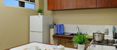 Una cucina con mobili in legno, un frigorifero bianco, un fornello e un tavolo da pranzo apparecchiato con piatti, tazze e posate.