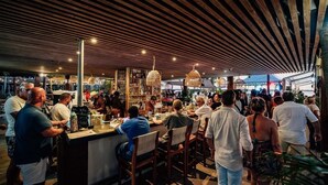 A crowded bar area with wooden slatted ceilings and hanging light fixtures. - Eden Beach Resort (Kralendijk)