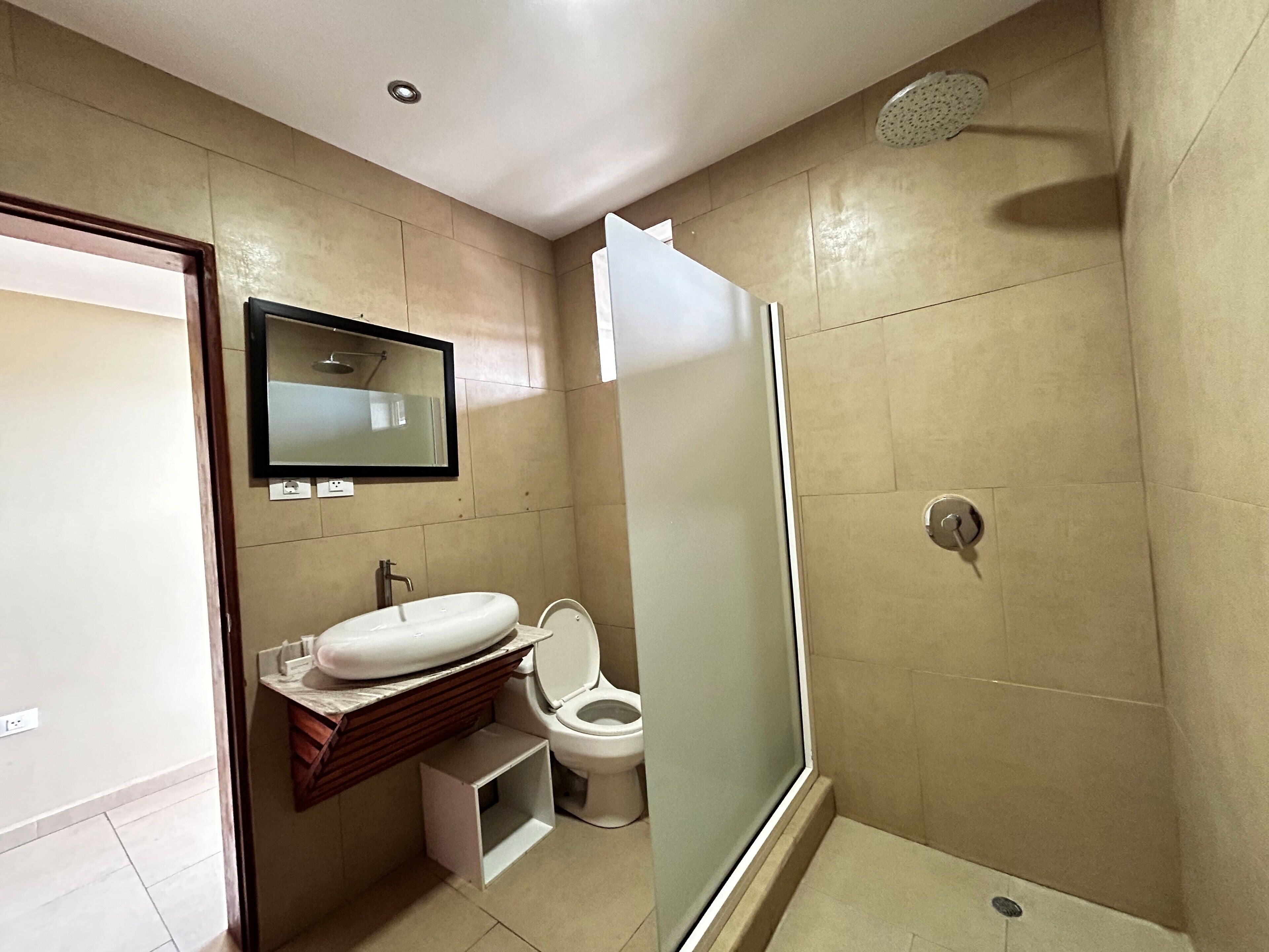 A modern bathroom with a toilet, sink, mirror, and shower.