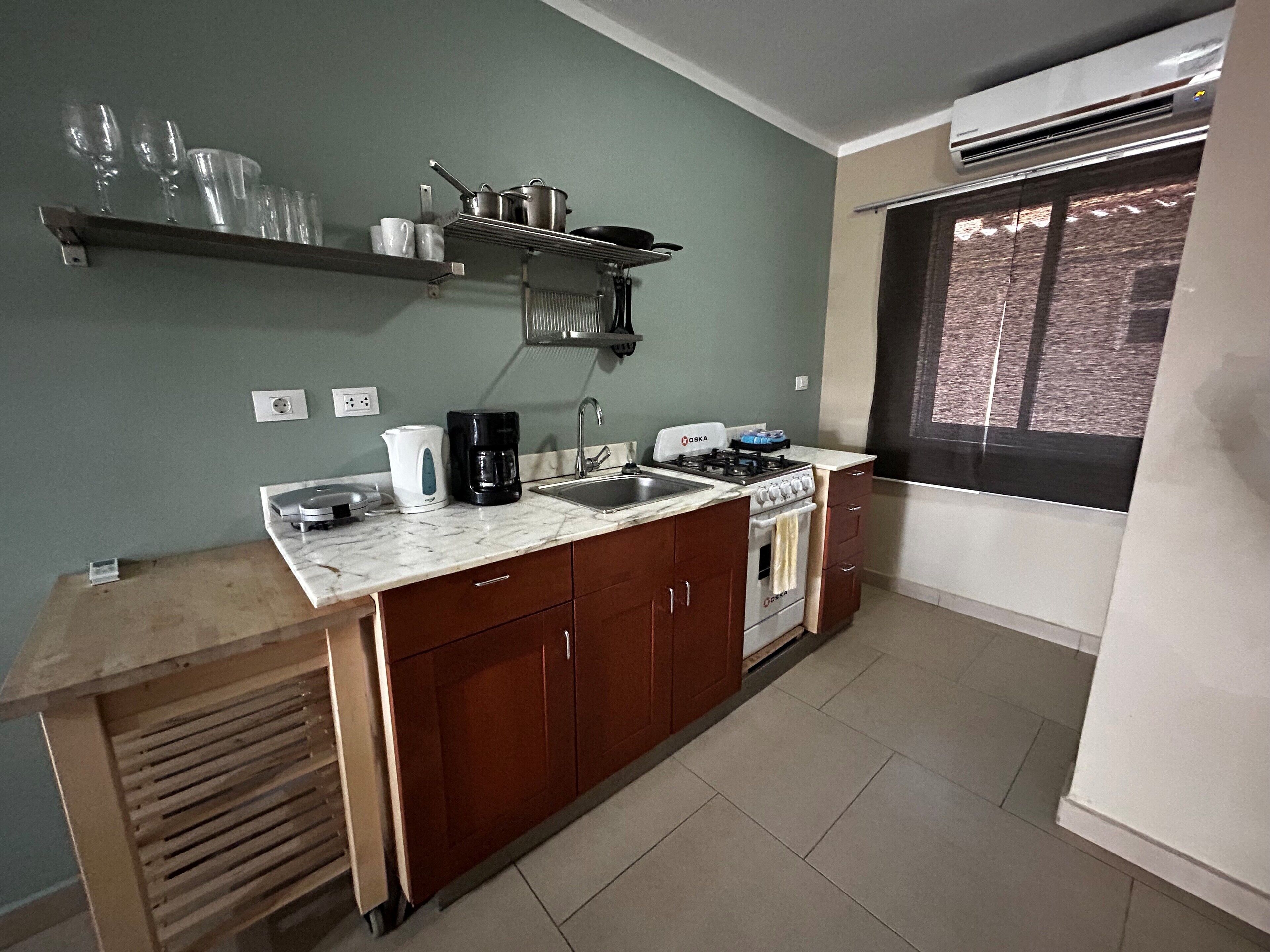A compact kitchen with a sink, stove, and a window with a view.