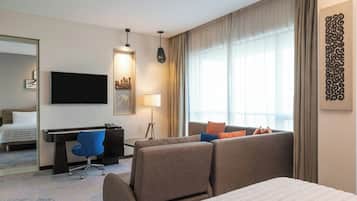 A hotel room with a bed, a desk with a chair, a TV, and a sofa.
