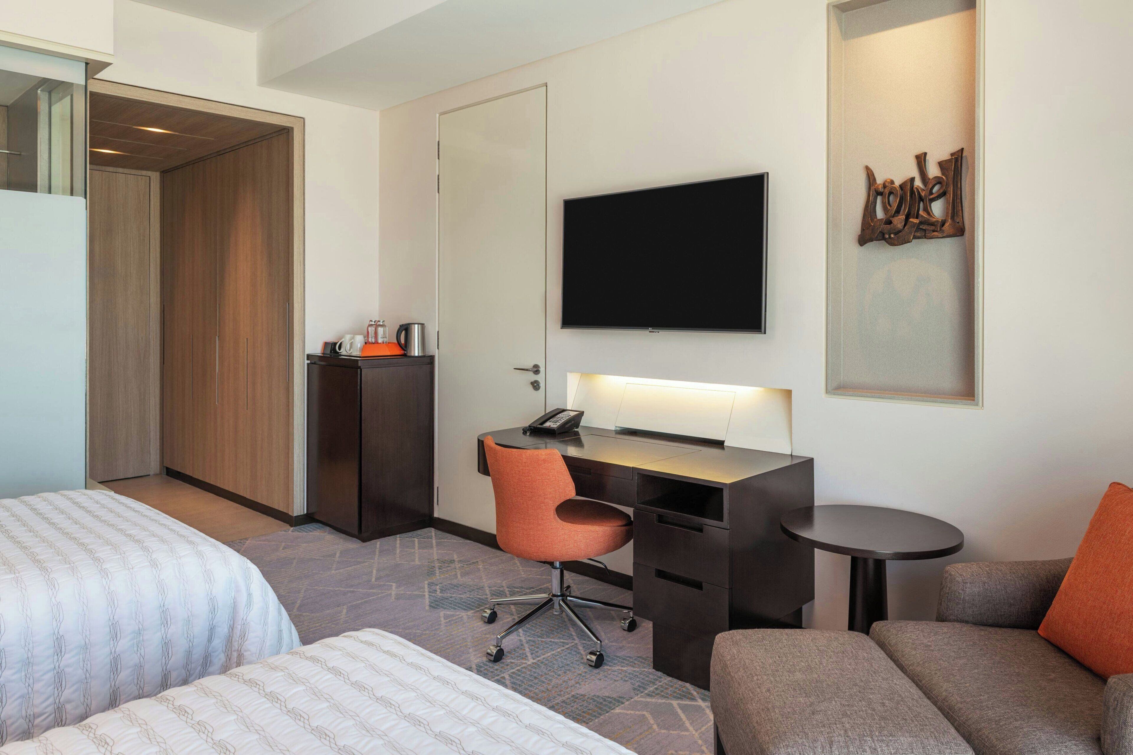 Una habitación de hotel con dos camas, un escritorio con una silla, un televisor y una mesita.