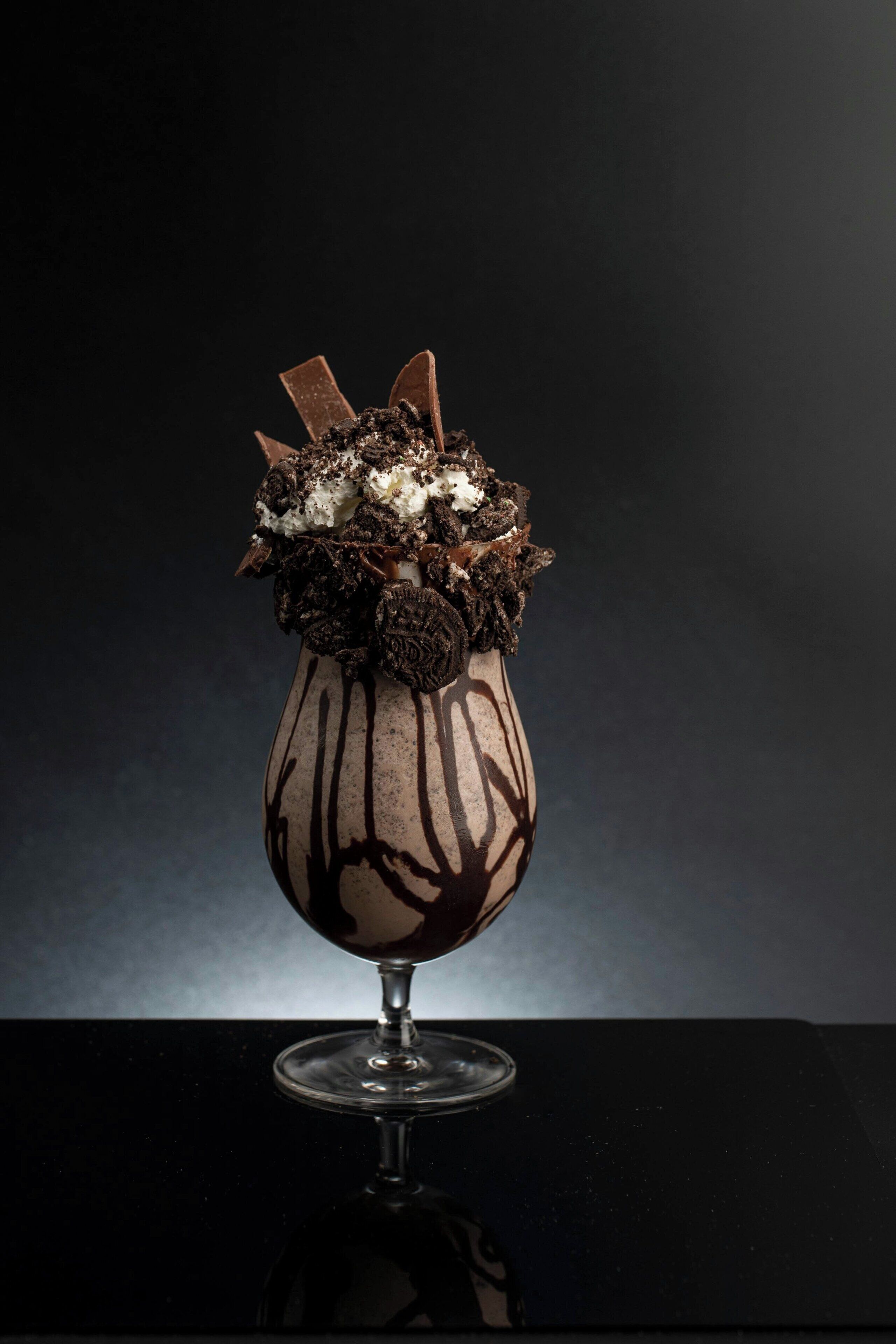 A dessert in a glass with chocolate and Oreo pieces on top.