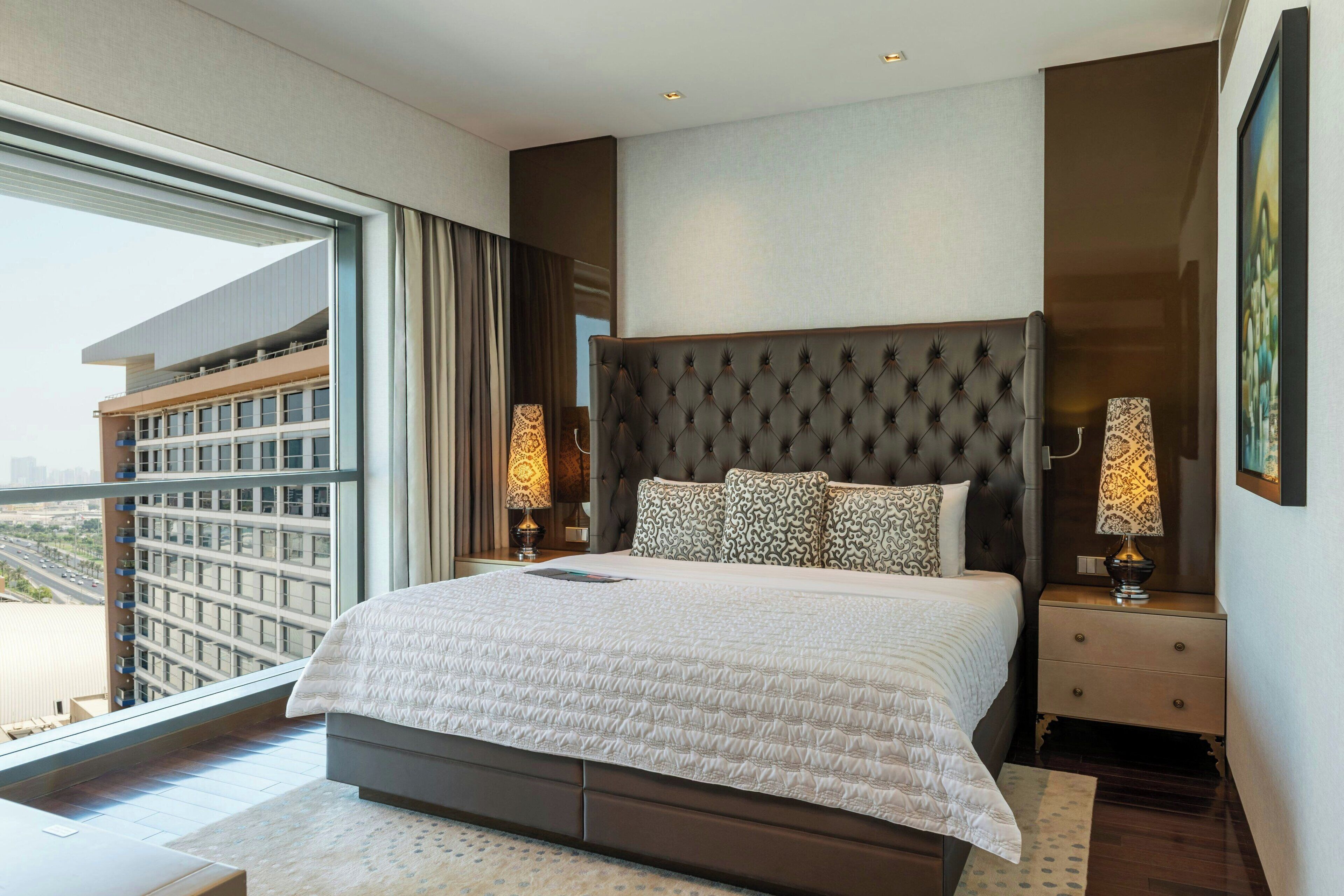 A modern hotel room with a large bed, a view of the city, and a balcony.