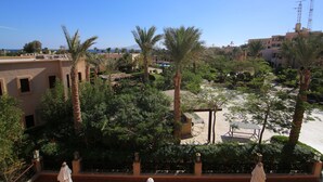 A courtyard with palm trees, a pool, and buildings in the background. - Tamra Beach Resort (Sharm El Sheikh)
